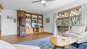A living room with a fireplace, a television, and a sofa. - Evelyn's River Front Retreat- Spacious House with Modern Comforts and Nature (Cushing)