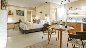 A modern hotel room with a bed, a dining table, chairs, a kitchen area, and a bathroom. - spectacular apartasuit in hotelb outique (Santa Marta)