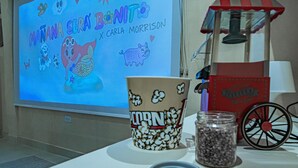 A projector screen with a cartoon character and text, popcorn containers, a jar of chocolate chips, and a popcorn machine. - spectacular apartasuit in hotelb outique (Santa Marta)