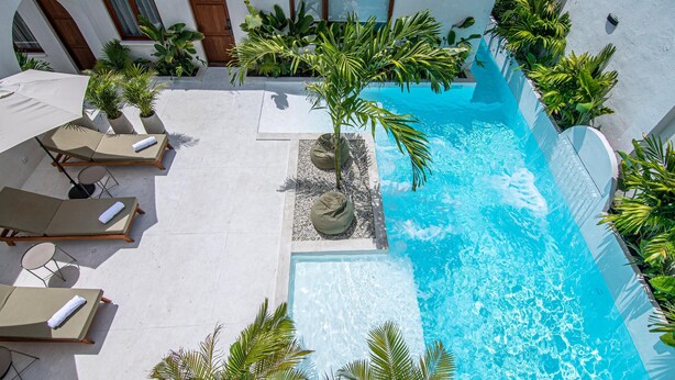 A rooftop pool with lounge chairs, a palm tree, and a small waterfall feature. - spectacular apartasuit in hotelb outique (Santa Marta)
