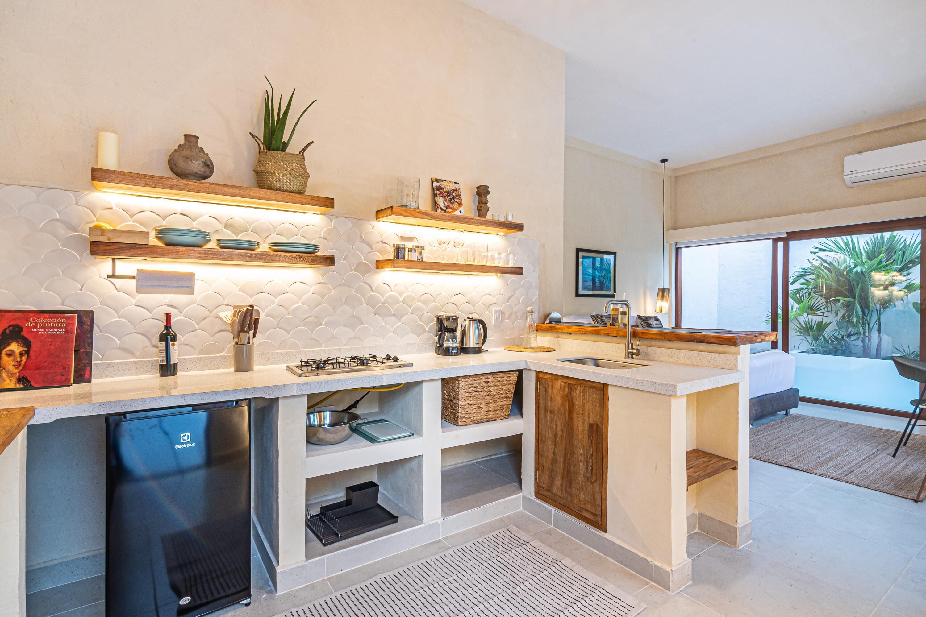 A modern kitchen with built-in shelves, a refrigerator, and a window to the right.