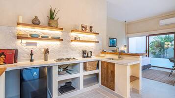 A modern kitchen with built-in shelves, a refrigerator, and a window to the right.