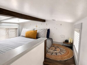 Un dormitorio con cama, mesita de noche, adorno de estrella en la pared y alfombra circular.