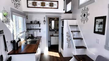 Un espace de vie compact comprenant une kitchenette, un coin repas et un escalier.
