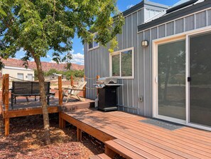 A deck with a grill and seating area, a sliding glass door, and a view of red rock formations. - Zion Stargazing Oasis • Pet Friendly • Sleeps 2 (Apple Valley)
