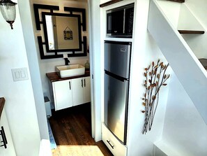 Una cocina moderna con armarios blancos, un refrigerador de acero inoxidable y un microondas.