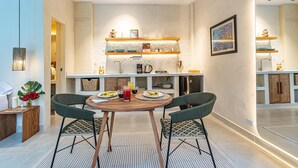 Een moderne keuken met een eethoek, inclusief een kookeiland, inbouwplanken en een eettafel met stoelen.