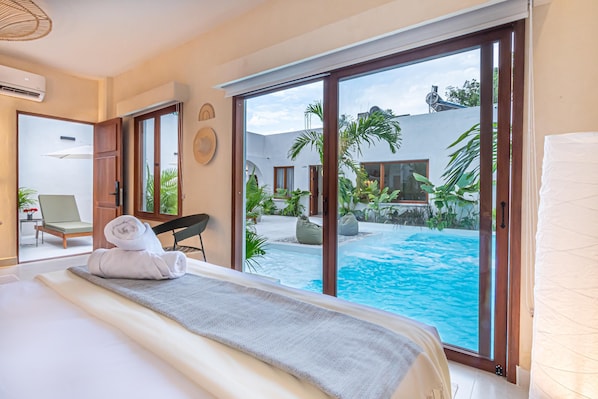 A hotel room with a bed, a view of a swimming pool, and a door leading to a balcony. - Apartasiote with pool views (Santa Marta)