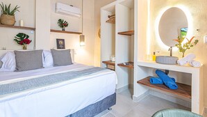 Un dormitorio con una cama, mesitas de noche, un espejo y un aire acondicionado de pared.