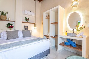 A bedroom with a bed, bedside tables, a mirror, and a wall-mounted air conditioner. - Delixe room in hotel boutique (Santa Marta)