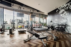 Ein modernes Fitnessstudio mit Cardiogeräten, Gewichtecken und Wandgemälden.