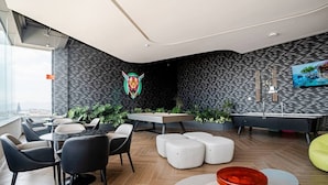 Un salon moderne doté d’une table de billard, de coins salon et offrant une vue sur la ville.