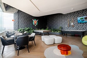 Eine moderne Lounge mit Billardtisch, Sitzgelegenheiten und Blick auf die Stadt.