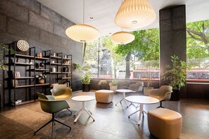 Ein modernes Interieur mit Bücherregal, Sitzecke und großen Fenstern.