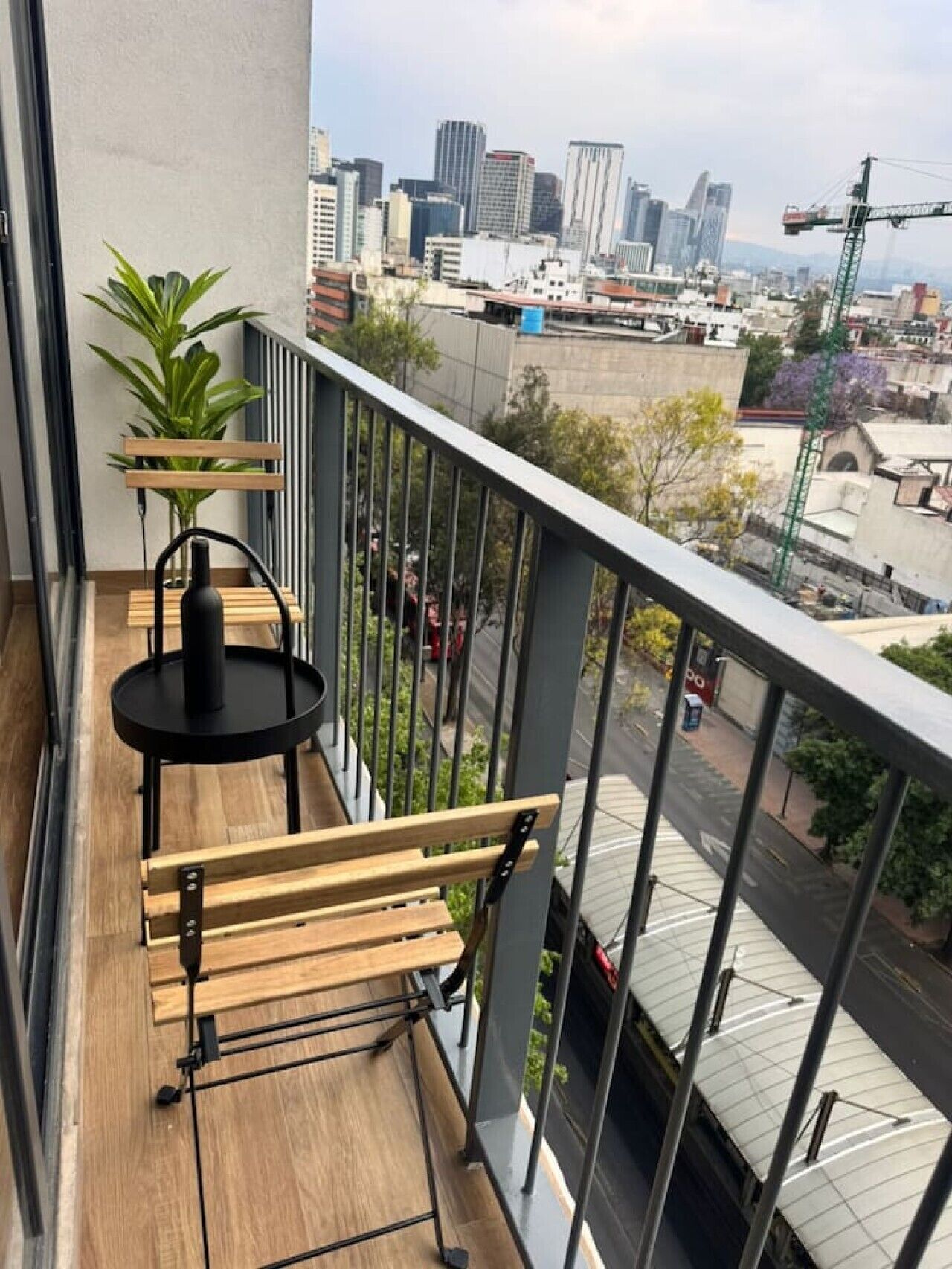 Ein Balkon mit einer hölzernen Bank, einem kleinen Tisch und einem Blumentopf.