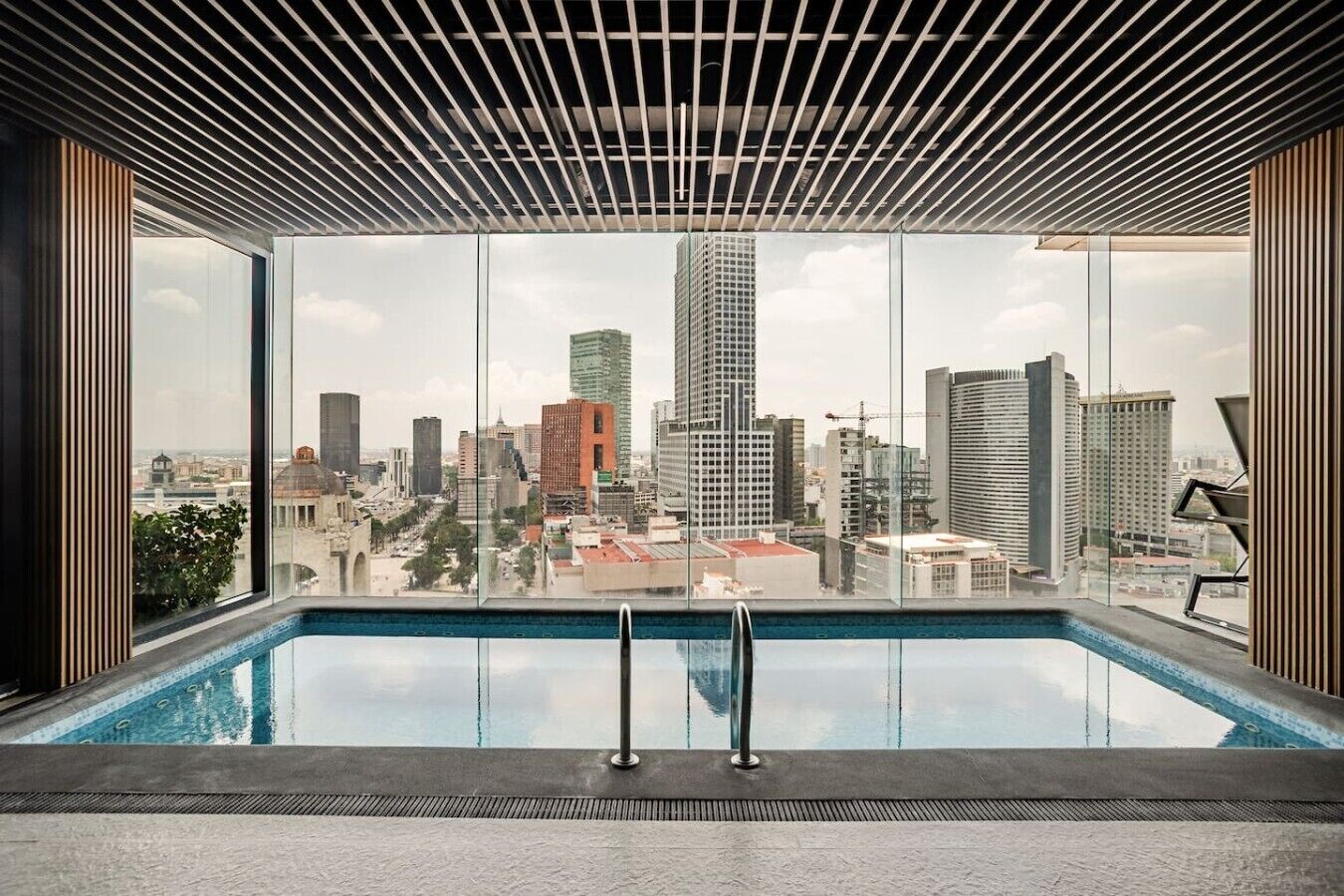 Una piscina interior moderna amb vistes a la ciutat a través de grans finestres.