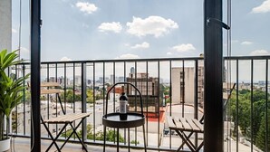 Un balcon donnant sur un paysage urbain, une bouteille de vin et deux chaises en bois.