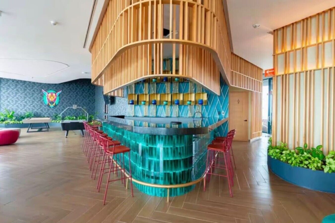 Eine moderne Bar mit einer gebogenen Holzkonstruktion, einem Billardtisch und roten Barhocker.
