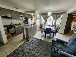 Una cocina moderna con comedor, una alfombra gris y un sofá gris.