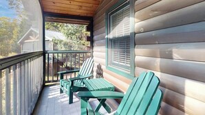 A wooden cabin with a porch, two Adirondack chairs, and a window with blinds. - Charming dog-friendly studio cabin with firepit and outdoor activities (Northport)