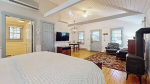 A spacious room with a large bed, a television, a fireplace, and a dining area. - Charming dog-friendly studio cabin with firepit and outdoor activities (Northport)