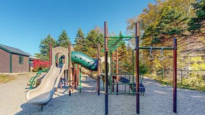 A playground with a slide, climbing structures, and a covered area. - Charming dog-friendly studio cabin with firepit and outdoor activities (Northport)