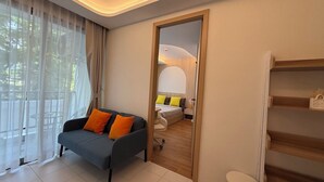 Een moderne woonkamer met een bank, een eethoek met tafel en stoelen, en een zicht door een deur naar een andere kamer.