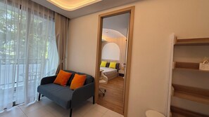 A modern living room with a sofa, a dining area with a table and chairs, and a view through a doorway to another room. - Kamala Beach Residence A202 (Tambon Kamala)