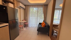 Een ruimtelijk ingerichte leefruimte met kitchenette, eethoek en zithoek met een bank en stoelen.