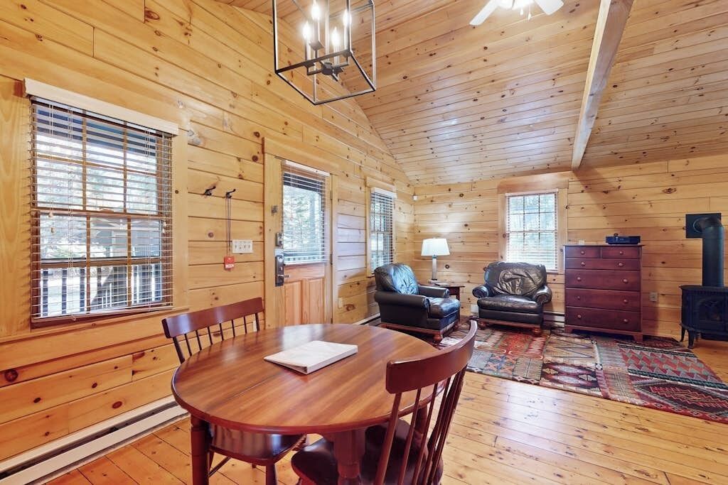 L’intérieur d’un chalet en bois comprend une table à manger, des chaises, un canapé, une lampe et une commode.