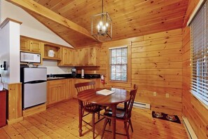 Ein Holzblockhaus-Interieur mit Küche, Esstisch und Stühlen.