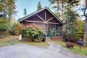 Une cabane avec un toit à forte pente, un porche à l’avant et une boîte aux lettres.