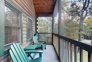 A wooden cabin with a porch, two Adirondack chairs, and a view of a forest. - Tranquil dog-friendly cabin with full kitchen, fireplace & nearby recreation (Northport)