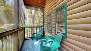 A log cabin with a porch, two green Adirondack chairs, and a view of the forest. - Bobcat Cabin, dog-friendly cabin retreat with full kitchen, outdoor activities (Northport)