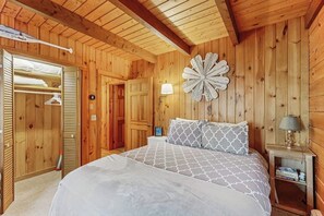 A wooden-paneled room with a bed, a wardrobe, and a wall-mounted decorative piece. - Charming riverfront home with cozy interiors, dock, and scenic deck views (Westport Island)
