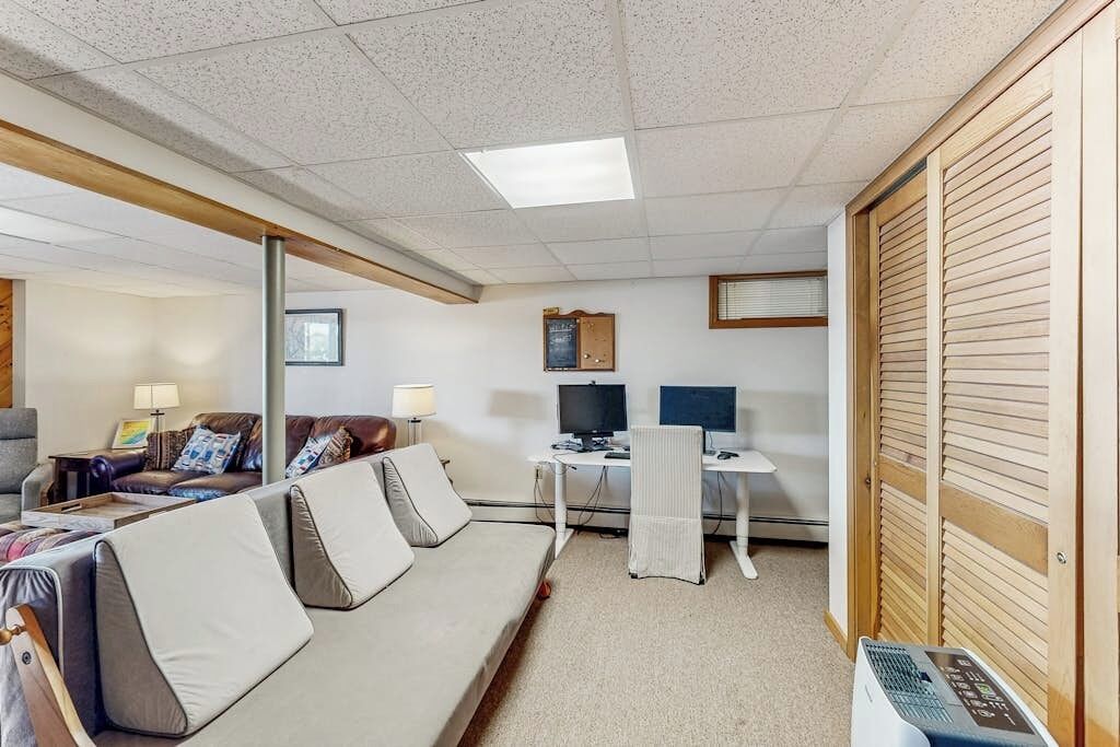 A hotel room with a sofa, a desk with a computer, a TV, and a wooden wardrobe.