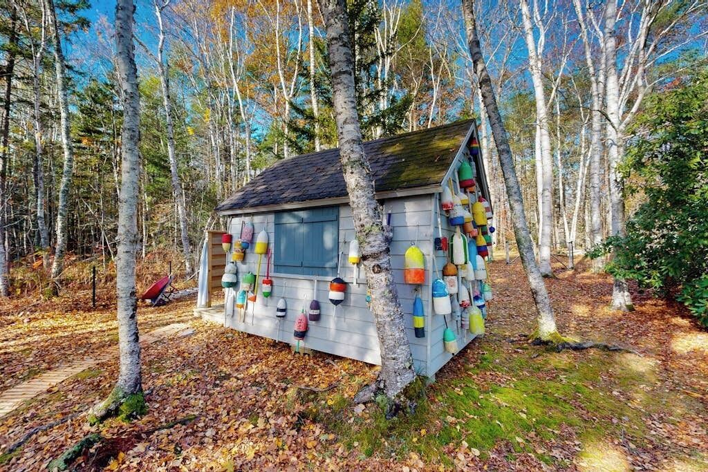 Une petite cabane au toit en pente, entourée d’arbres.