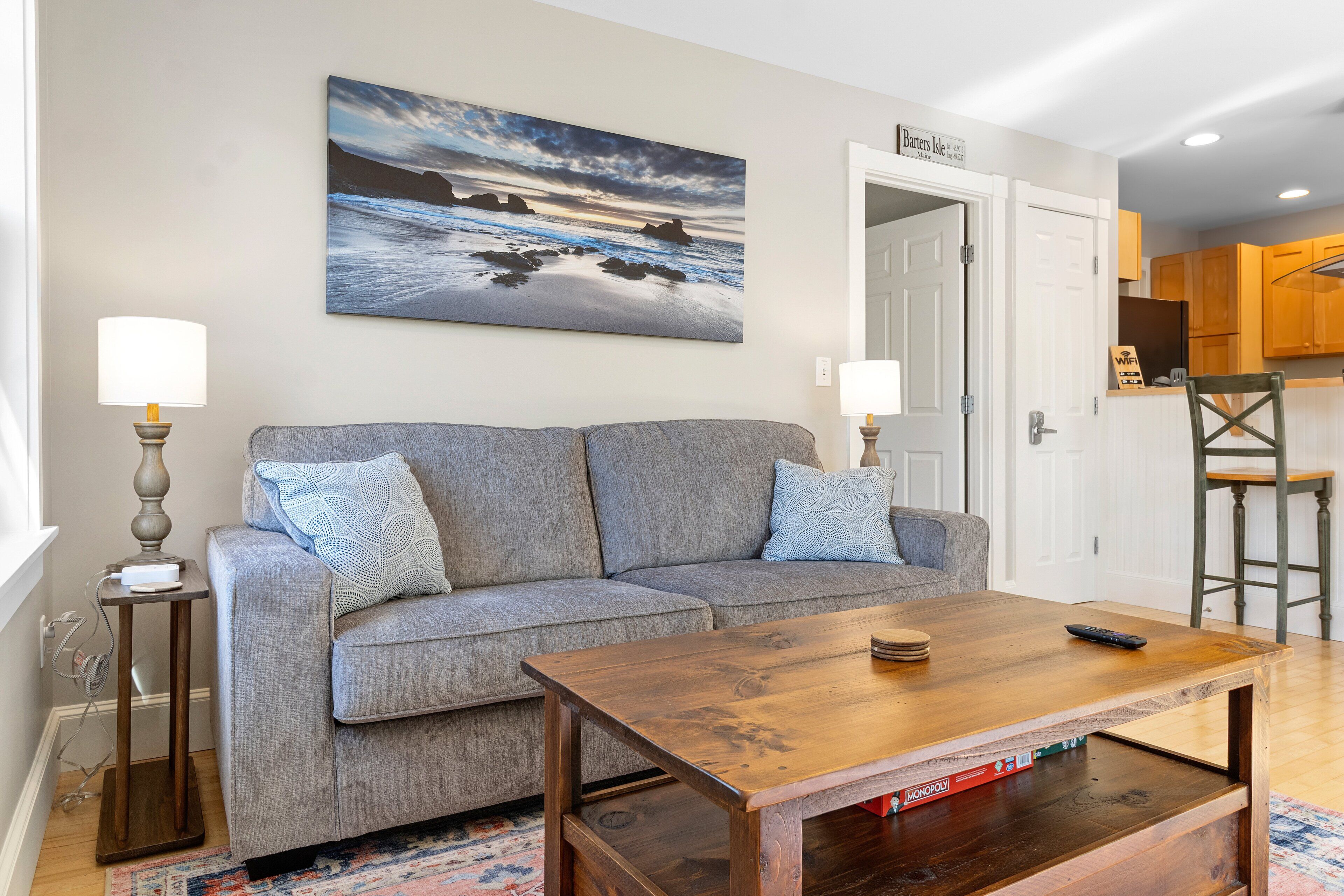 A living room with a sofa, coffee table, and artwork on the wall.