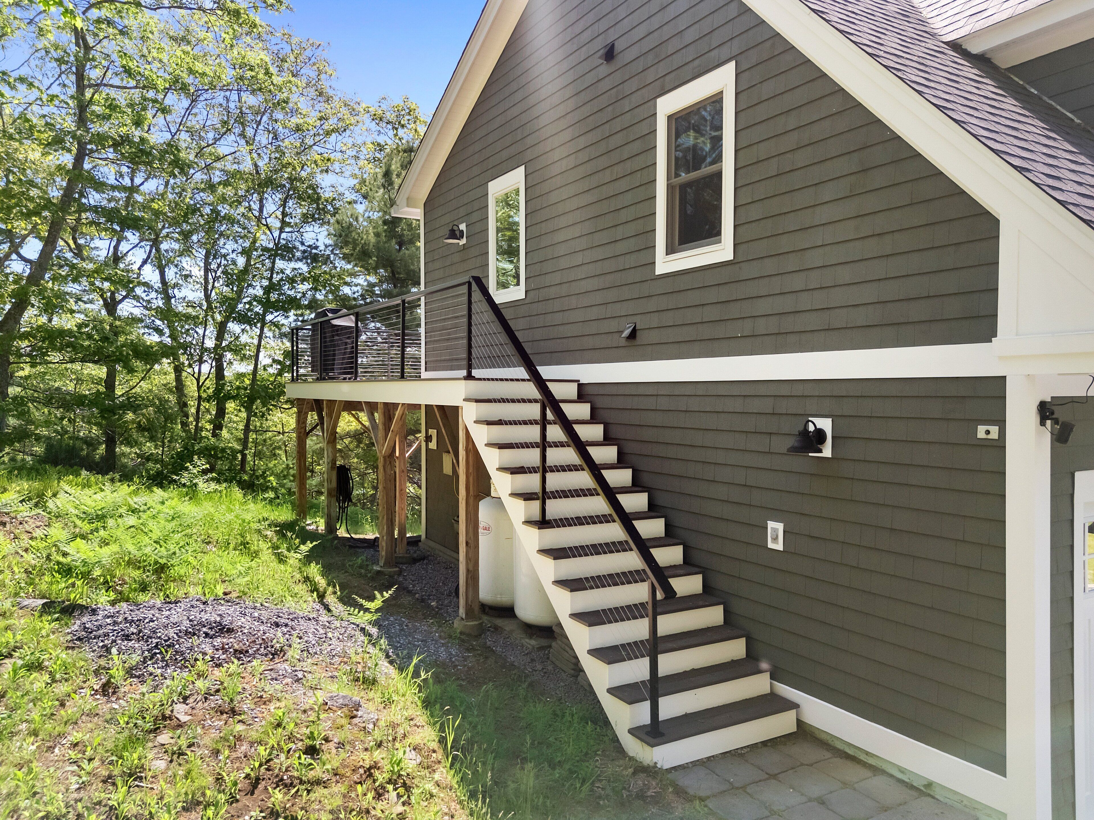 A two-story house with a wooden deck, a staircase, and a garage.