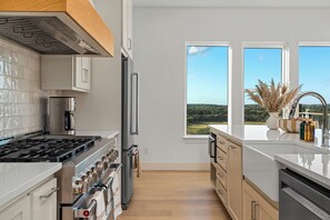 Eine moderne Küche mit Herd, Kühlschrank und großen Fenstern mit Blick auf die Landschaft.
