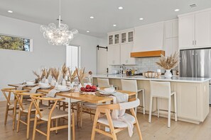 Eine moderne Küche mit weißen Schränken, einem Edelstahl-Kühlschrank und einem Essbereich mit Holzkohle und einer zentralen Kücheninsel.
