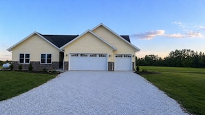 A two-story house with a gravel driveway, a garage, and a lawn.