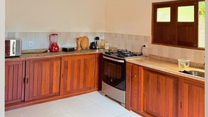A kitchen with wooden cabinets, a gas stove, a microwave, and a blender. - Beautiful Leisure House (Trancoso)
