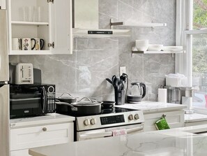 A modern kitchen with a built-in oven, microwave, and stove. There are cabinets above the counter and a window providing natural light. - Ramblei near Drexel Park: 4-Bedroom Unit A (Philadelphia)