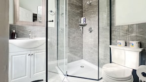 Une salle de bain moderne avec une douche à parois de verre, un lavabo blanc et des toilettes.