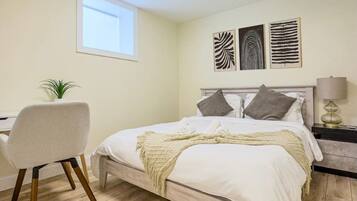 A bedroom with a bed, bedside table, lamp, chair, and a window.