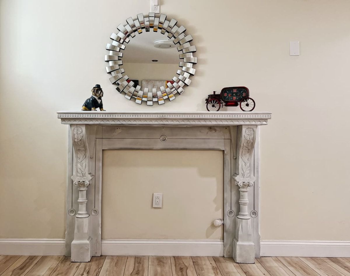 A fireplace with a decorative mirror above it and a toy train on the mantel.