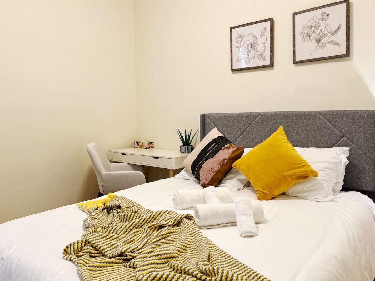 Ein Hotelzimmer mit einem Bett, einem Schreibtisch und zwei gerahmten Pflanzenabbildungen an der Wand.