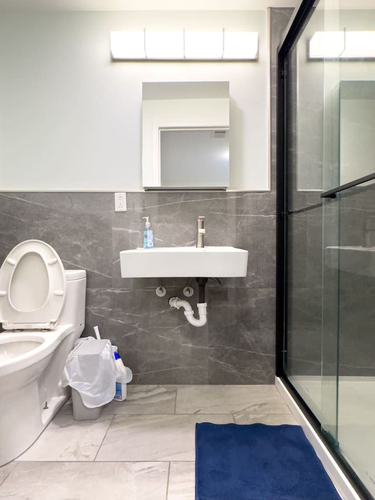 A bathroom with a toilet, sink, and glass shower enclosure.