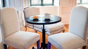 Une table ronde avec une tasse et un muffin, deux chaises et une fenêtre donnant sur un paysage enneigé.